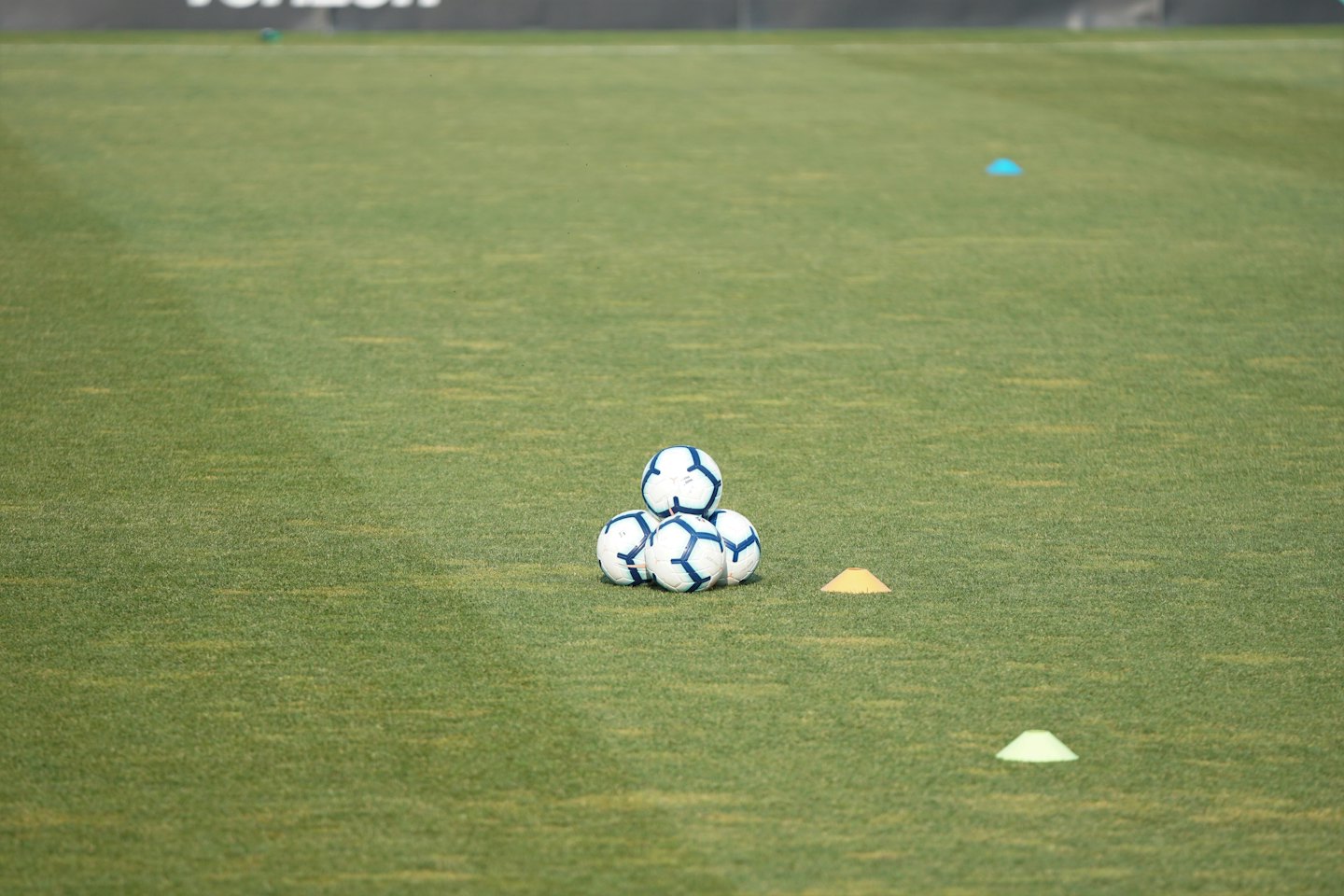 Soccer balls and training cones on an artificial turf field.