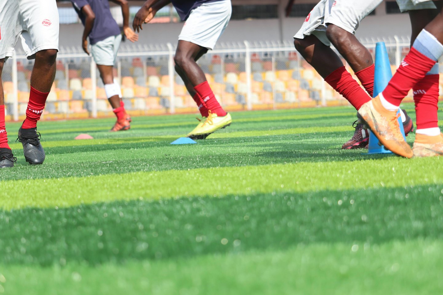Football players practicing drills on a green turf field.